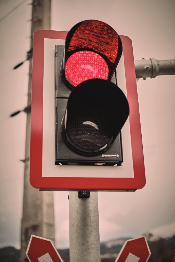 Imagem mostras semáforo com farol vermelho acionado.